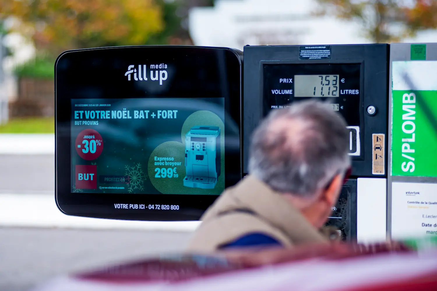 Homme qui regardent une publicité en faisant le plein
