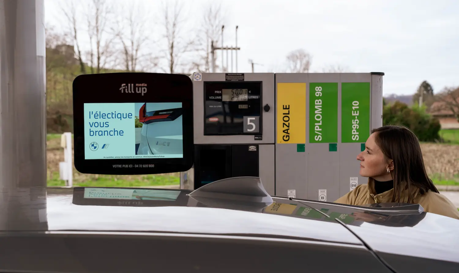 Automobiliste regardant une publicité pendant son plein d'essence