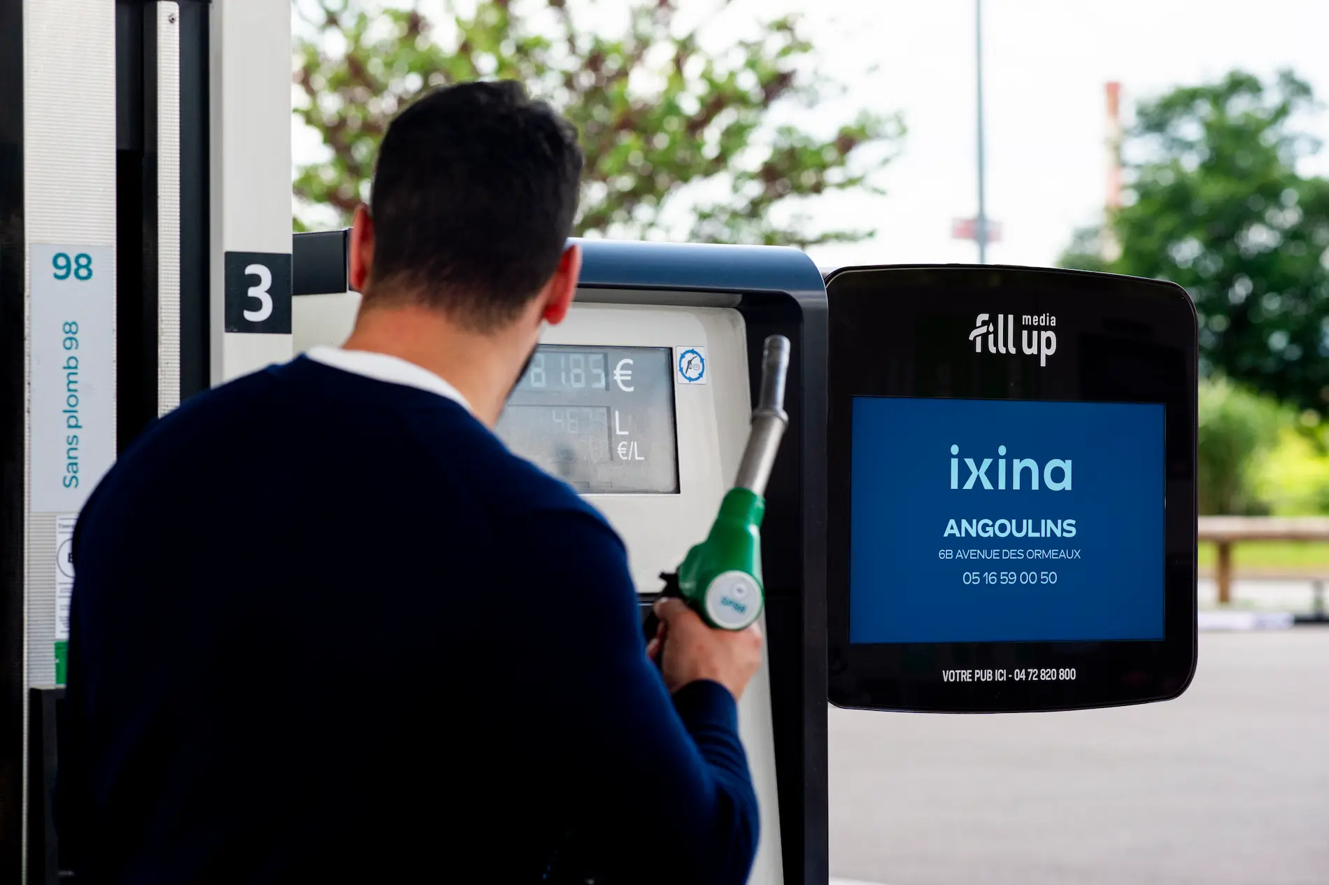 un homme faisant son plein et regardant une pub