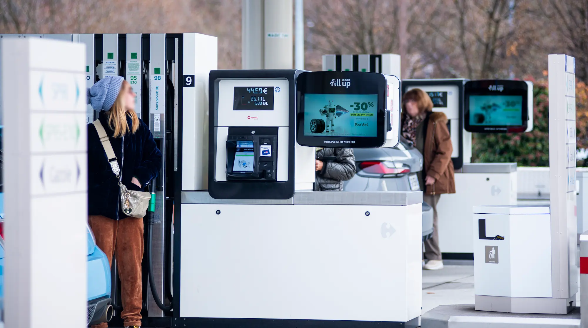 fum-le-media-affichage-digital-station-service Femmes regardant un écran publicitaire pendant le plein